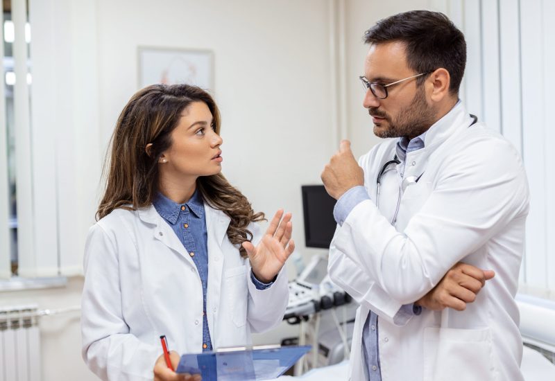 confident-doctors-discussing-medical-chart-male-female-healthcare-workers-are-wearing-lab-coats-they-are-working-hospital